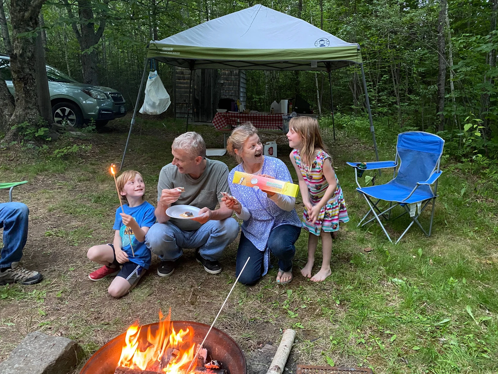 Owner and family roasting marshmallows by campfire